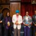 Tiya wearing black with a purple scarf holding her colorful award, standing with the other award winners.